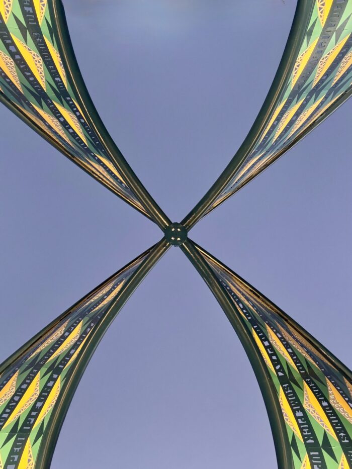 “Energetic” sculpture by artist Blessing Hancock in Fort Worth’s Sycamore Park — a colorful, figure-eight-shaped metal artwork with curving forms and community-inspired text bands, fabricated and installed by Gizmo Art Production.